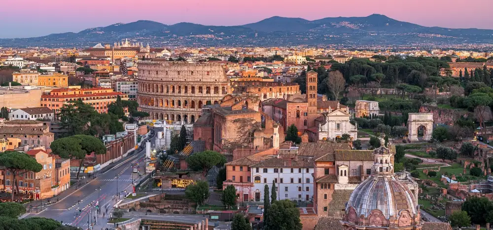 Rome skyline at sunset with the Colosseum and Roman Forum in the foreground
